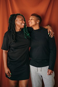 Happy lesbian couple standing by a red background