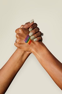 LGBT couple with a painted rainbow flag tattoo holding hands