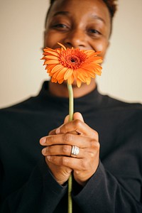 Happy black woman holding a daisy flower