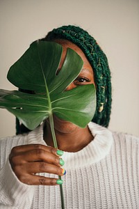 Happy black woman holding a leaf over her face