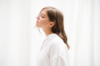 Woman in a white linen shirt by the curtains