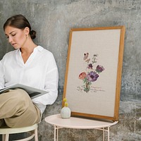 Woman sitting on a stool and reading a book by a photo frame