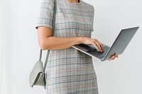 Woman in a gray plaid dress using a laptop