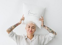 Tattooed woman holding a feminine pillow mockup over her head