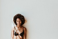 Black woman in a bra standing against a white wall