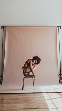 Black woman curling up on a chair in a studio