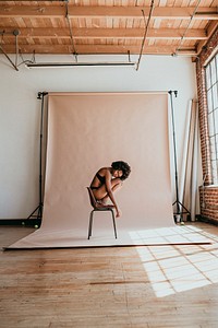 Black woman curling up on a chair in a studio