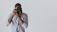 Black photographer capturing a picture with a retro film camera