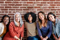 Diverse women sitting together by a brick wall 