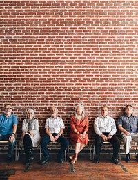 Diverse elderly people sitting in a row against a brick wall background