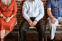 Diverse elderly people sitting in a row against a brick wall background