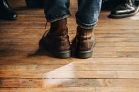 Man in a brown leather boots standing on a wooden floor