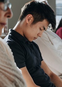 Tired young Asian man falling asleep in a seminar