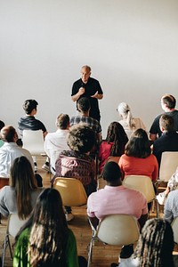 Elderly man speaking on a microphone in a seminar