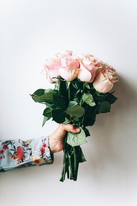 Woman holding a bouquet of flowers by the wall