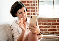 Happy woman waving hello to a smartphone