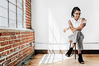 Cheerful woman sitting on a chair using smartphone