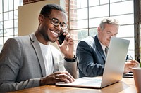 Businessman talking on a phone while using a laptop