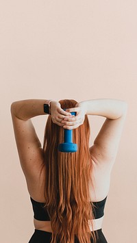 Rear view of woman lifting dumbbells to tone her arms mobile phone wallpaper