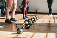 People standing by kettlebells in the gym