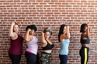 Group of sportive women standing by a brick wall