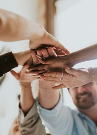 Happy team putting their hands together for success