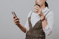 Businesswoman drinking coffee while checking her phone