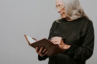 Senior businesswoman writing down on a notebook