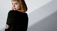 Brown hair woman in a black fluffy sweater looking back over her shoulder