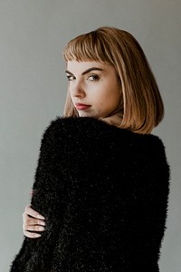 Brown hair woman in a black fluffy sweater looking back over her shoulder