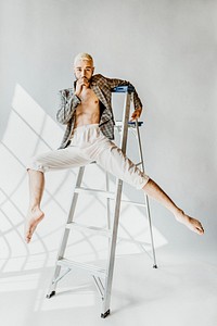 Gay man in a plaid coat posing on a step ladder