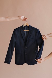 Hands holding a black blazer in a hanger