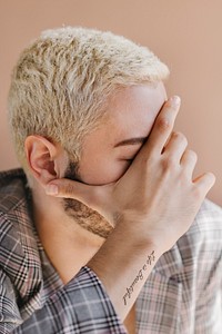 Tattooed man covering his face with a hand mockup