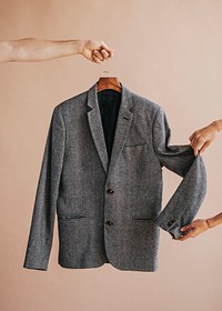 Hands holding a gray blazer in a hanger