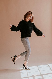 Brown hair woman in a black fluffy sweater hopping with high heels