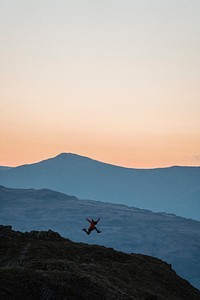 Woman jumping on a summit of Loughrigg Fell at Lake District in England
