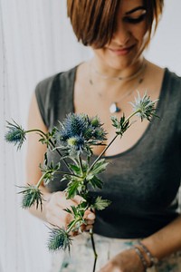 Cheerful woman holding a blue thistle