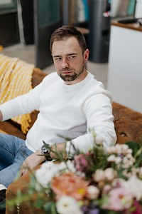 Man sitting on the couch by the flowers