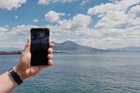 Man using his smartphone to capture the scenic ocean