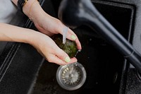 Woman washing an avocado at a sink