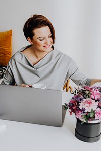 Cheerful woman reading a book by her laptop