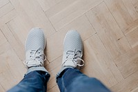Woman in gray sneakers standing on a wooden floor