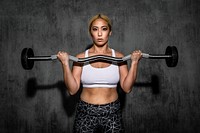 Woman exercising weighlifting with barbell at fitness gym