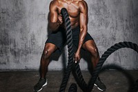Muscular man doing a battle rope in a gym