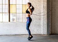 Sporty woman jumping skipping rope at gym