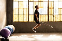 Sporty man jumping skipping rope at gym