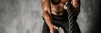 Muscular man working out on the battle ropes in a gym