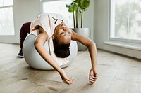 Black woman doing stretching on a balance ball