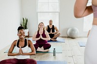 Cheerful people doing a Sukhasana pose in a studio
