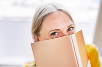 Woman hiding behind a shiny gold notebook